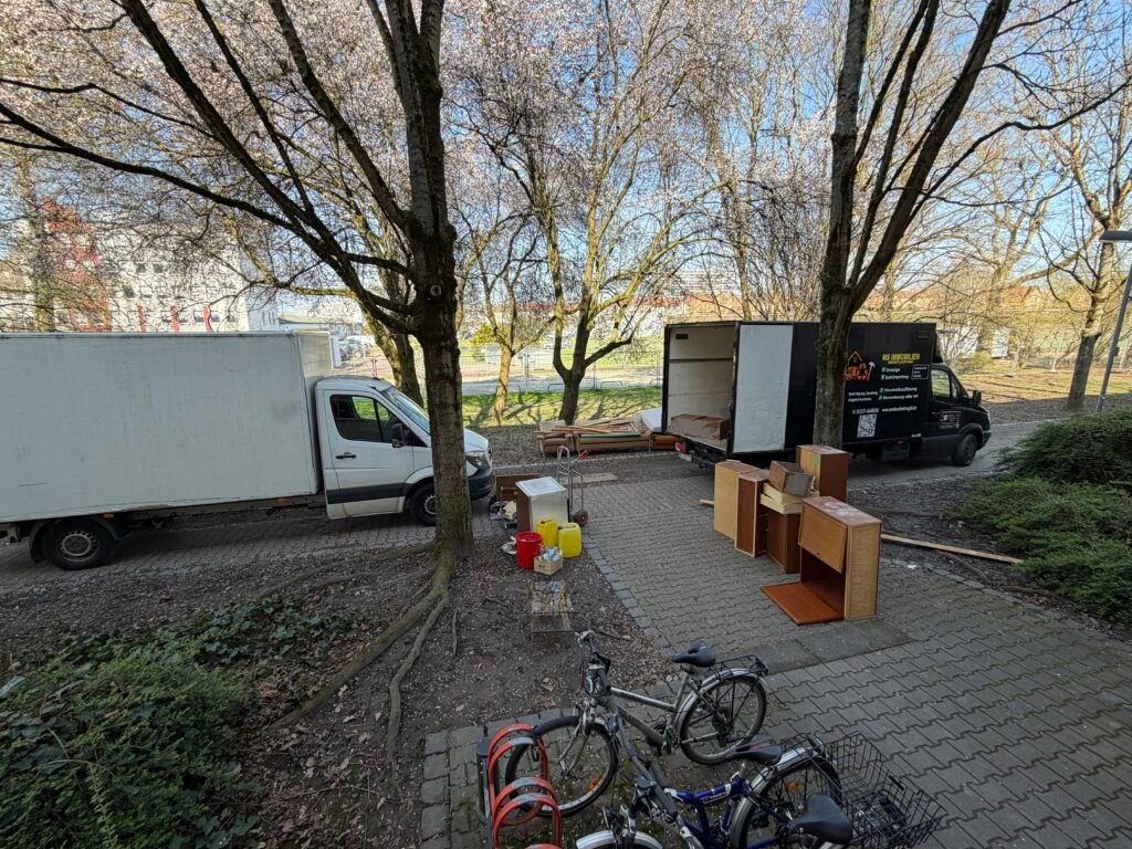 Messie-Entrümpelung in Frankfurt: zwei LKW vor dem Wohnhaus, davor ausgeräumte Möbel und Hausrat